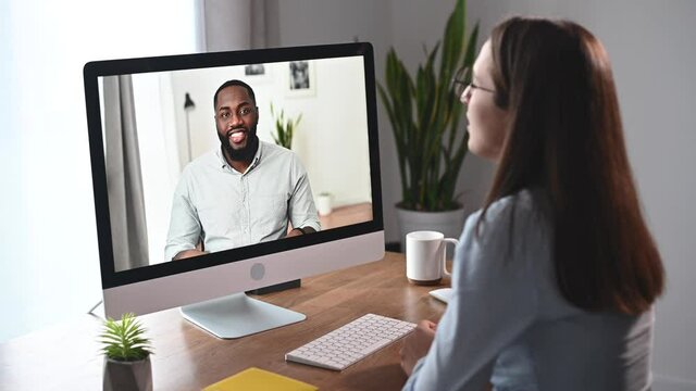 Online interview concept. An African American applicant is talking on the laptop screen, an hr employee listening. Video meeting, virtual conference of diverse work team