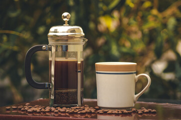 Preparando una taza de café en prensa francesa o cafetera de embolo con granos de café molidos en molinillo artesanal 
