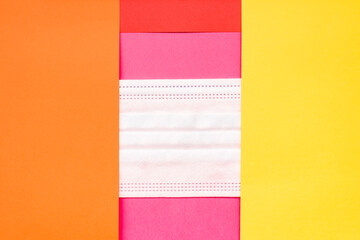A sanitary mask between papers of various colors, background to fill.