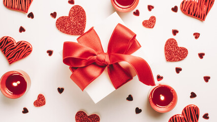 Saint Valentin background: red love hearts, romantic gift box, candle on white table. Romantic message template with copy space. Top View. View from above.