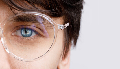 Close up view of blue male eye in glasses with futuristic holographic interface to display data. Portrait of beautiful young man, half of face. Augmented reality, future technology, internet concept.