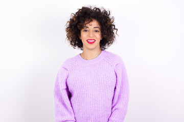 young beautiful caucasian woman wearing pink knitted sweater against white wall with nice beaming smile pleased expression. Positive emotions concept