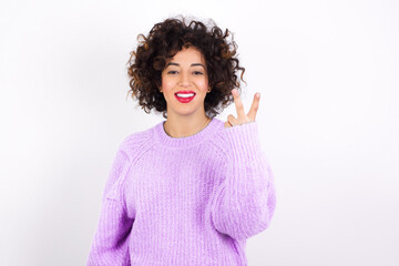 young beautiful caucasian woman wearing pink knitted sweater against white wall smiling and looking friendly, showing number two or second with hand forward, counting down