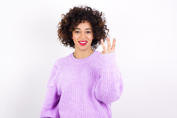 young beautiful caucasian woman wearing pink knitted sweater against white wall smiling and looking friendly, showing number three or third with hand forward, counting down