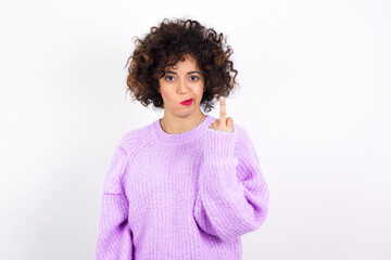 young beautiful caucasian woman wearing pink knitted sweater against white wall shows middle finger...