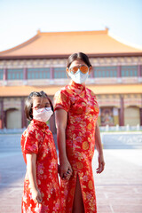 asian woman and girl wearing red chinese suit and wearing face protection mask standing outdoor