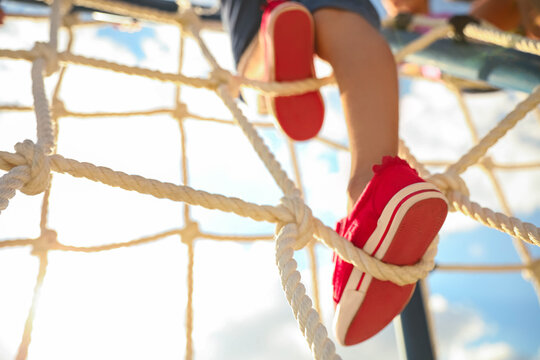 Child on playground rope climber outdoors, closeup. Summer camp