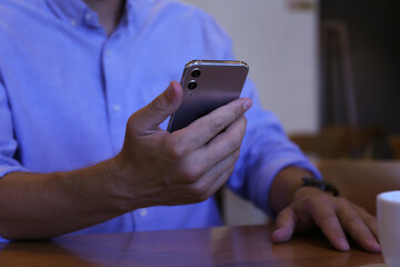 Businessman with modern smartphone in cafe, closeup