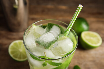 Delicious mojito and ingredients on wooden background, closeup