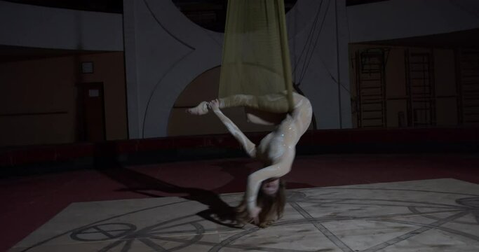 Aerial tricks performed by an athletic young woman hanging upside down, 4k