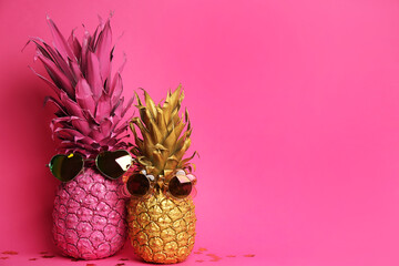 Painted pineapples with sunglasses on pink background, space for text. Creative concept
