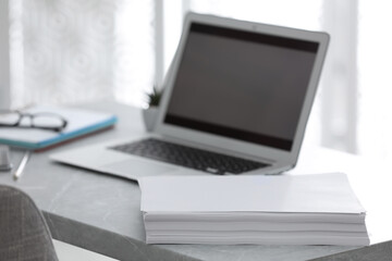 Stack of blank paper sheets on grey table in office, closeup