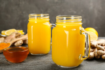 Two mason jars of immunity boosting drink and ingredients on grey table, closeup