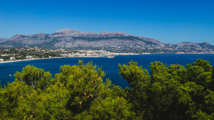 Naklejka na ściany i meble Panoramic coastal view to Atea over mediteranean sea and blurred pines in natural park 'Serra Gelada' in Albir, Spain