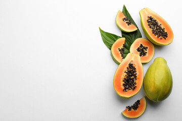 Fresh ripe papaya fruits with green leaves on white background, flat lay. Space for text