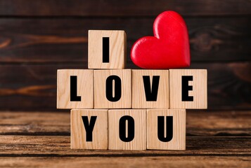 Cubes with words I Love You and red heart on wooden table