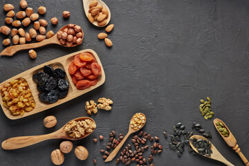 Fototapeta na wymiar Different kinds of nuts, dried fruits on black slate background. Top view with copy space. Healthy food. Vegetarian nutrition