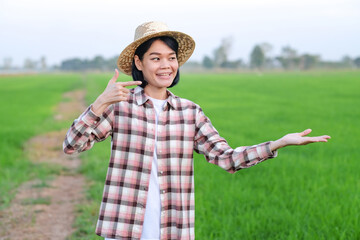 Asian farmer woman smile and looking  pose lift things at a green rice farm