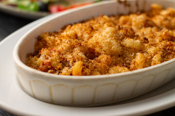 Casserole or lasagna, sprinkled with breadcrumbs in white oval ceramic baking dish