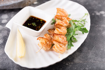 Grilled salmon skewers served with lemon and sauce. Top view