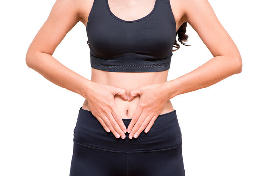 close up body of woman wearing sportswear and showing slim beautiful belly and making heart shape with her hands on her belly. isolated