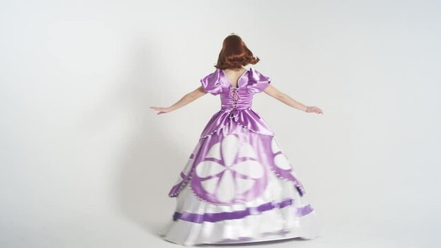 Portrait of a young cute girl in a beautiful princess costume isolated on white background. Bright colorful character with brown hair, purple dress and a crown on her head. Animators in costumes
