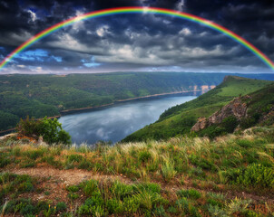 Obraz premium colorful rainbow over the river canyon. spring morning
