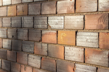 Full frame texture background of a vintage weathered tile brick wall with worn bricks having a scorched like appearance in colors of white, red, and brown