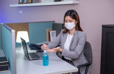 Safety work place concept, Young businesswoman wearing face mask and using Sanitizer hand gel while...