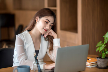 Pretty young asian businesswoman sitting in the office using a laptop computer.