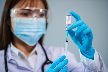 doctor drawing Coronavirus (Covid-19) vaccine bottle into syringe injection medicine