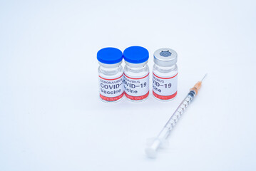 two medical syringes and three bottles of COVID-19 vaccines