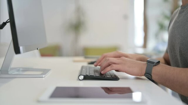 Hands of Young Man Typing on Keyboard of Desktop, Close Up 