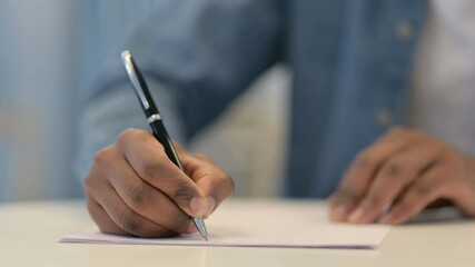 Hands of African Man Writing on Paper with Pen, Close Up