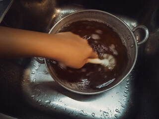 Cleaning wok with hot water and special dishwashing concentrate to remove old residue.