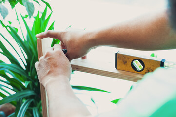Carpenter with pencil and the meter marks the measurement on a wooden board. DIY at home.