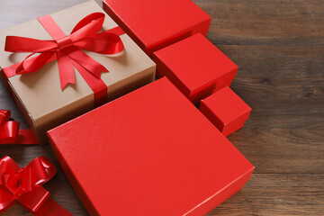 Brown and red gift boxes and red ribbon on wooden background with space