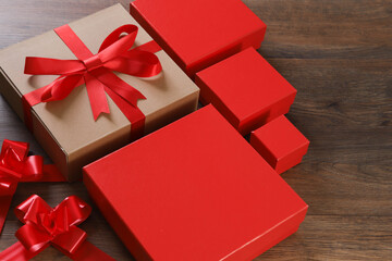 Brown and red gift boxes and red ribbon on wooden background with space