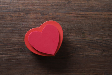 Red heart-shaped gift box on wooden background with space