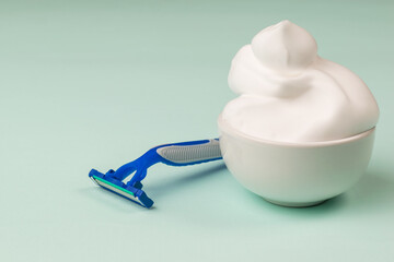 A large amount of shaving foam in the bowl and a disposable razor on a blue background.