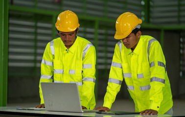 Engineer working at factory,Engineers in hard hats discuss new project while using laptop.