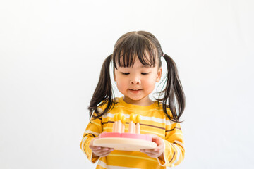 Cute adorable little asian toddler girl celebrating birthday while holding birthday cake wooden toy gift and blowing candles.Happy birthday party.isolated on white background at home.Happy Birthday.
