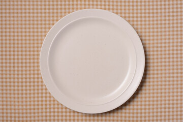 茶色いチェック柄の上の梨子地の皿