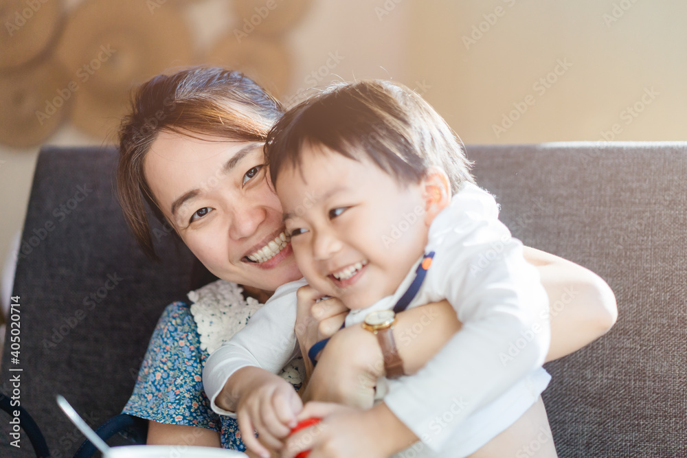 Wall mural Portrait of asian mother and toddler boy child playing having fun together. Happy son and mom laughing and kissing at home in breakfast.Love family lifestyle single mom.Mother’s day holiday concept.