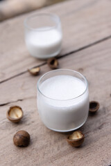 Macadamia milk in a glass with bark on wooden floor.Top view.