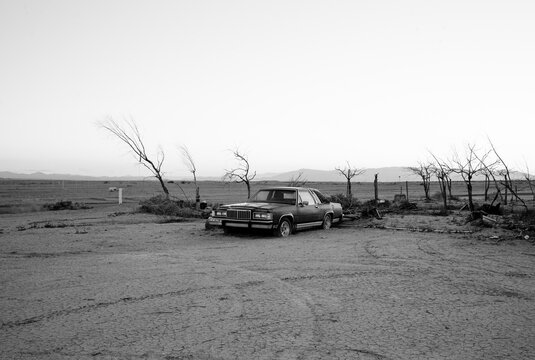 Grayscale photo of car parked in desert