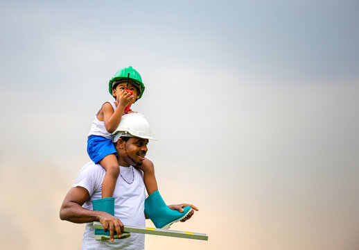 Cheerful african american father and son in hard hat, Happy dad carrying son on shoulders