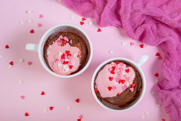 Two chocolate mug cakes with strawberry ice cream and heart sugar topping