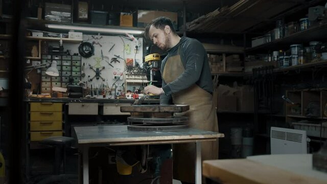 A carpenter paints a piece of wood for a loft-style chair with a brush. Close up