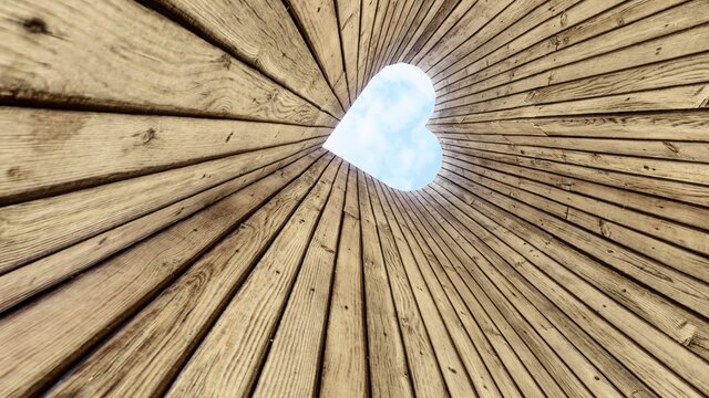 Coraz&oacute;n vista al cielo con duela de madera, una  perforaci&oacute;n que enmarca las nubes.
